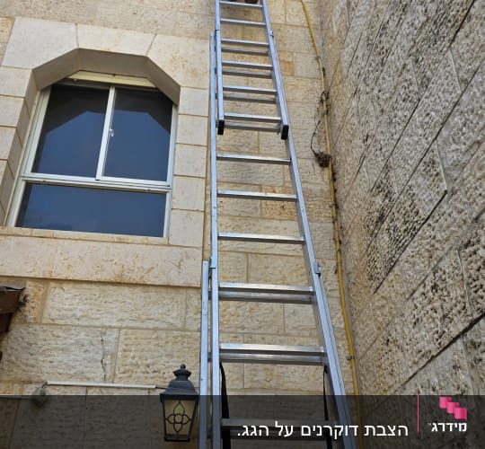 אדם על סולם ליד קיר אבן גבוה